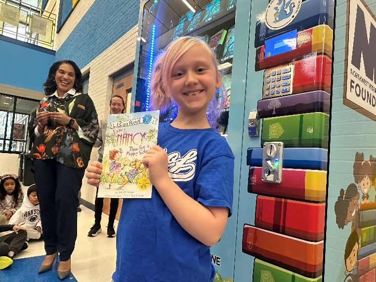 Jamie Gadley and elementary school student holding a book donated by NWFCU Foundation