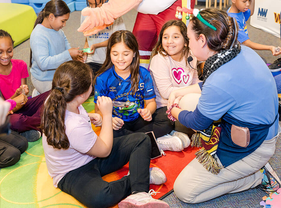 Foundation employee smiling with group of children during community youth program activity.